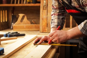 Carpenter marking a measurement on a wooden plank