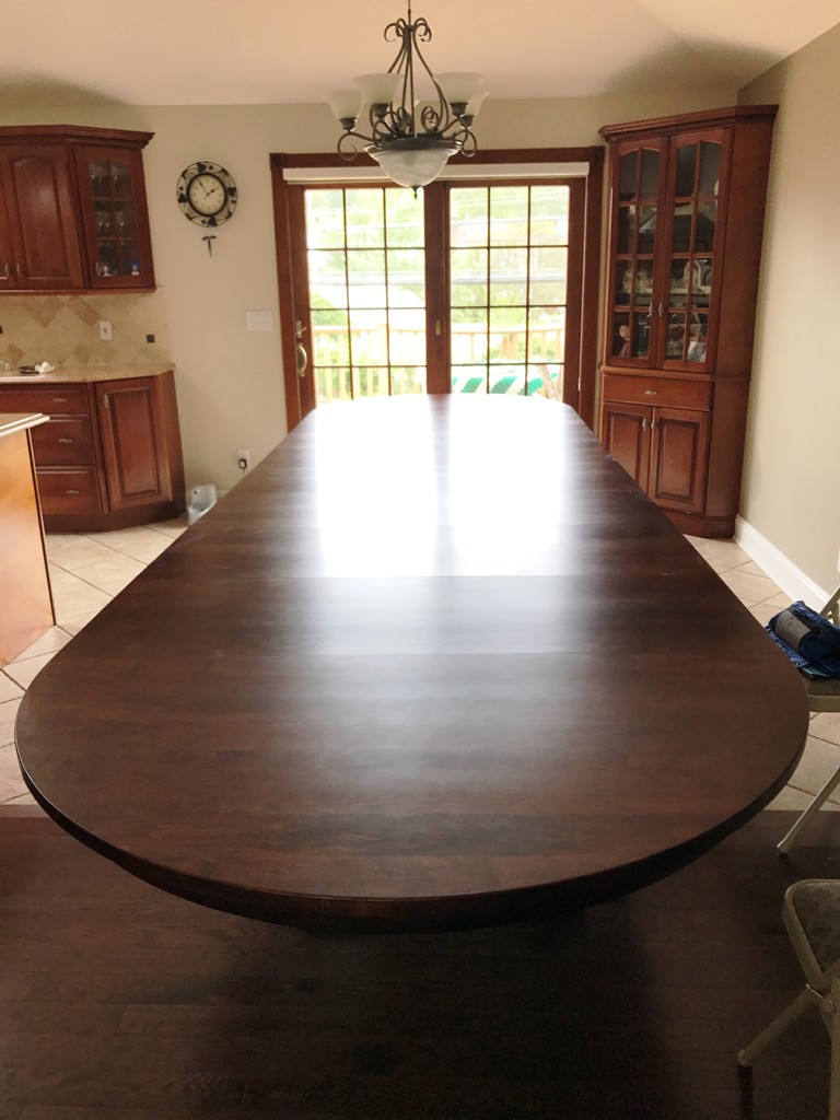 A Monteray Split Pedestal Dining Table in hard maple with Burnt Umber stain and a lot of leaves in—Amish Furniture Factory