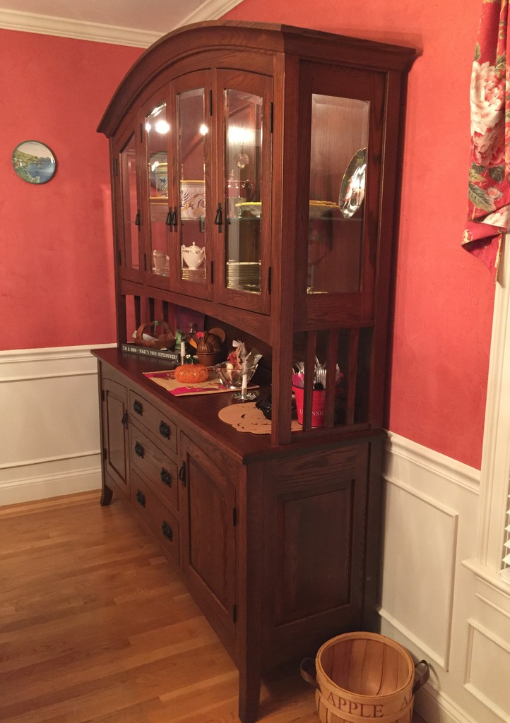 The Cambria Hutch from Amish Furniture Factory in oak with Old World Mission stain in a red dining room with floor-to-table-height white panels and honey colored hardwood floor