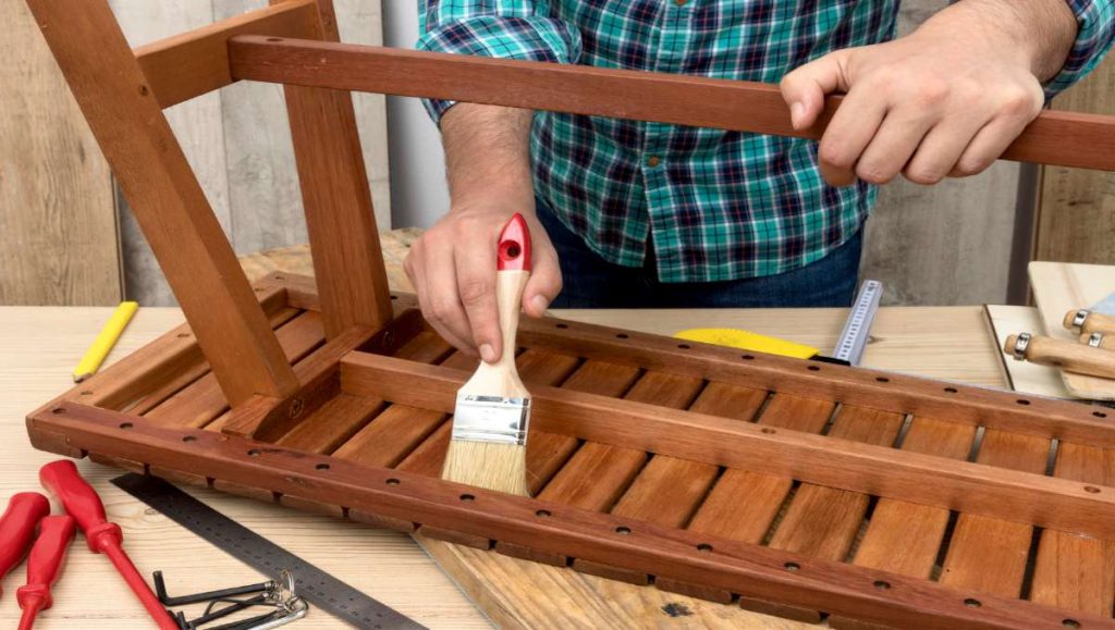 Man refinishing and painting wooden furniture