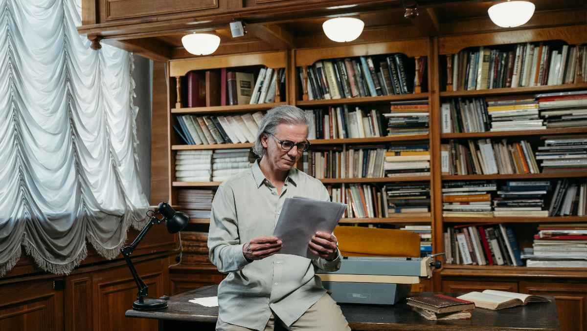 Man reading a book in front of barrister bookcase